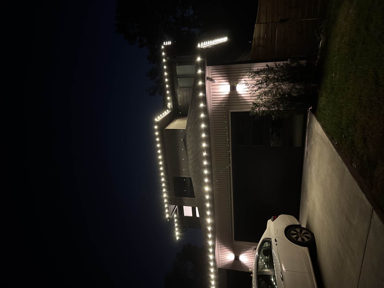Warm white roofline lighting on a modern home, evening view