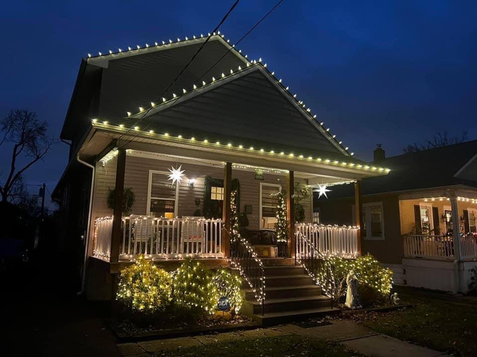 Front porch decorated with icicle lights, roofline lighting and lit star ornaments