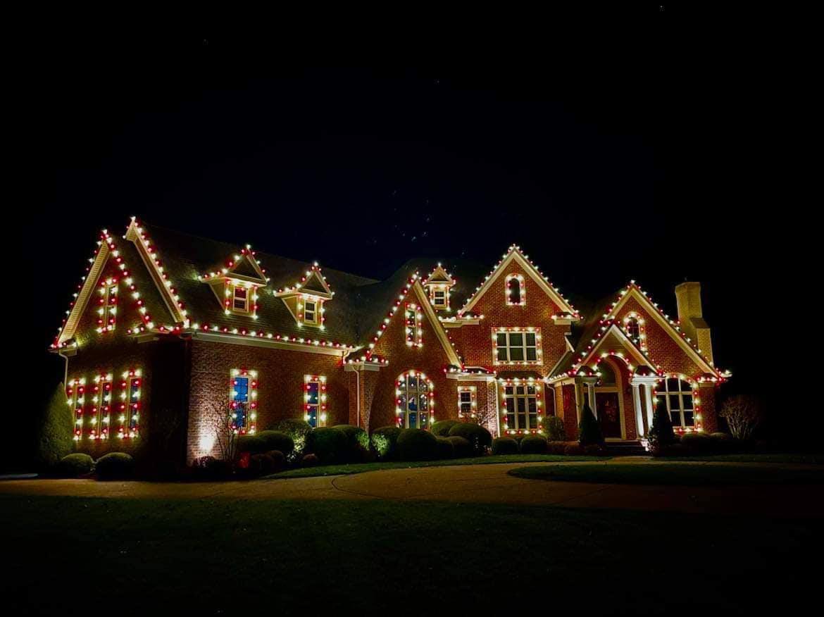 Elaborate red and green C9 lighting outlining a large estate home's roofline and windows